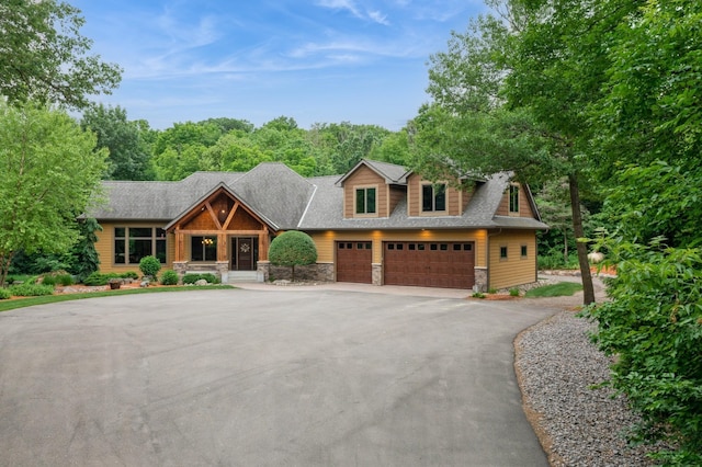 8271 Barton Ave NW, Buffalo, MN 55313 - view of front facade with stone siding, driveway, a shingled roof, and covered porch