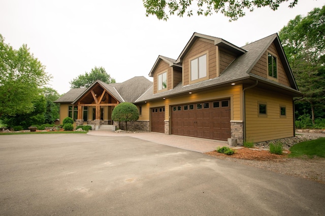 8271 Barton Ave NW, Buffalo, MN 55313 - craftsman house featuring stone siding, driveway, a porch, and a shingled roof