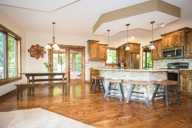 8271 Barton Ave NW, Buffalo, MN 55313 - kitchen featuring stainless steel appliances, brown cabinets, decorative backsplash, dark wood-style flooring, and light countertops