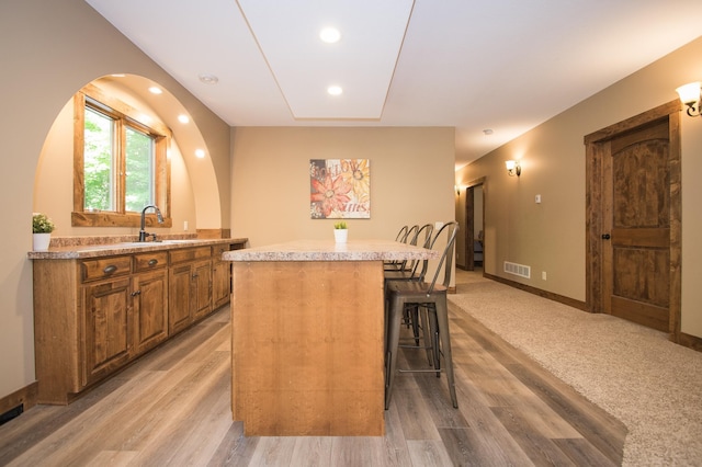 8271 Barton Ave NW, Buffalo, MN 55313 - kitchen with brown cabinets, a breakfast bar area, a center island, light countertops, and light wood-style flooring
