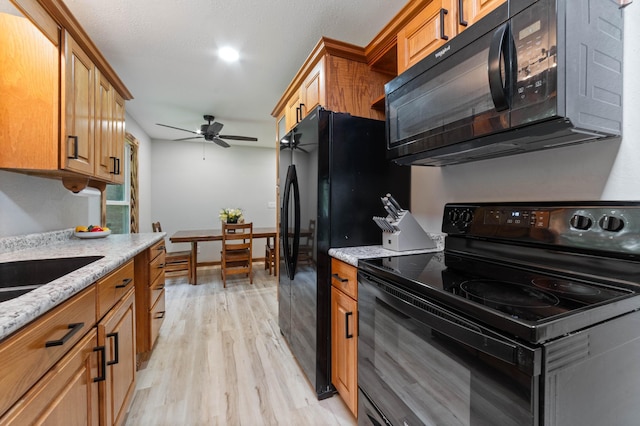 185 Olson Rd, Thomson Twp, MN 55733 - kitchen with black appliances, light wood-type flooring, ceiling fan, and light stone countertops