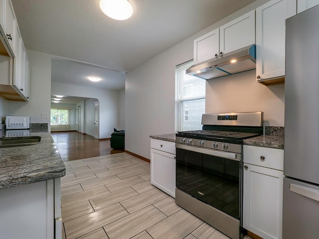 4021 Colfax Ave N, Minneapolis, MN 55412 - kitchen with appliances with stainless steel finishes, under cabinet range hood, white cabinetry, and wood finish floors