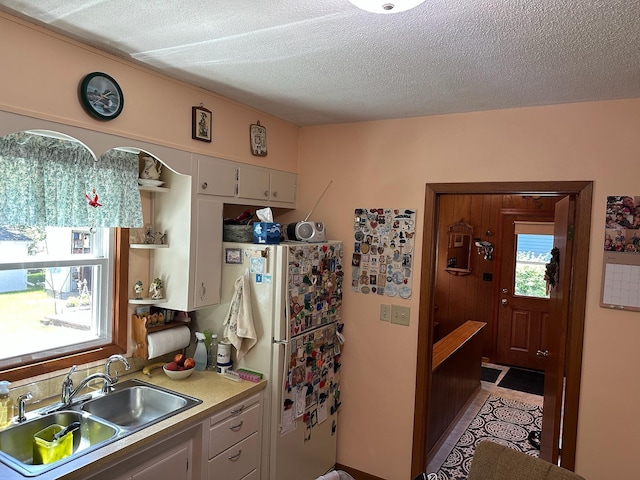 925 Willow St W, Detroit Lakes, MN 56501 - kitchen featuring open shelves, light countertops, a textured ceiling, freestanding refrigerator, and white cabinetry