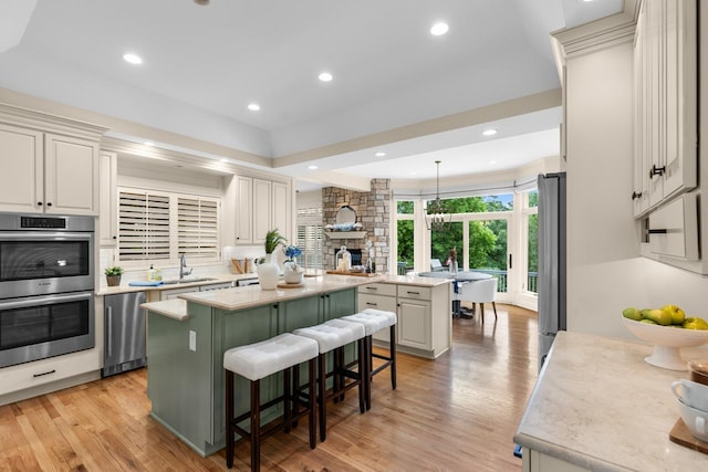11193 Bluestem Ln, Eden Prairie, MN 55347 - kitchen with stainless steel appliances, a center island, a stone fireplace, light wood finished floors, and light countertops