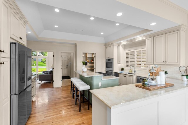 11193 Bluestem Ln, Eden Prairie, MN 55347 - kitchen featuring appliances with stainless steel finishes, a tray ceiling, backsplash, light wood-style floors, and a peninsula