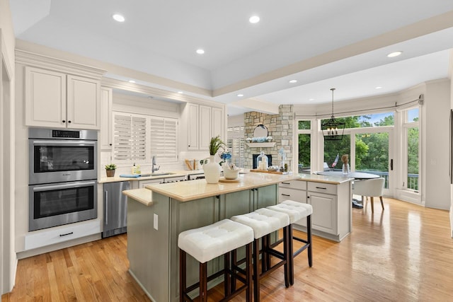 11193 Bluestem Ln, Eden Prairie, MN 55347 - kitchen with double oven, a kitchen island, light countertops, light wood-style flooring, and a breakfast bar