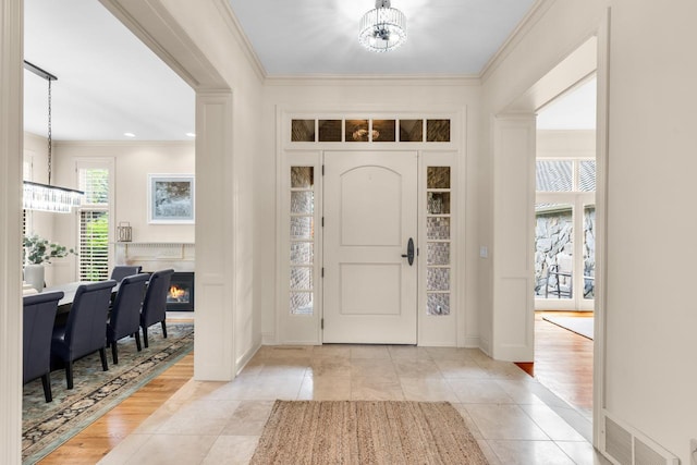 11193 Bluestem Ln, Eden Prairie, MN 55347 - tiled entryway featuring a chandelier, ornamental molding, and a warm lit fireplace