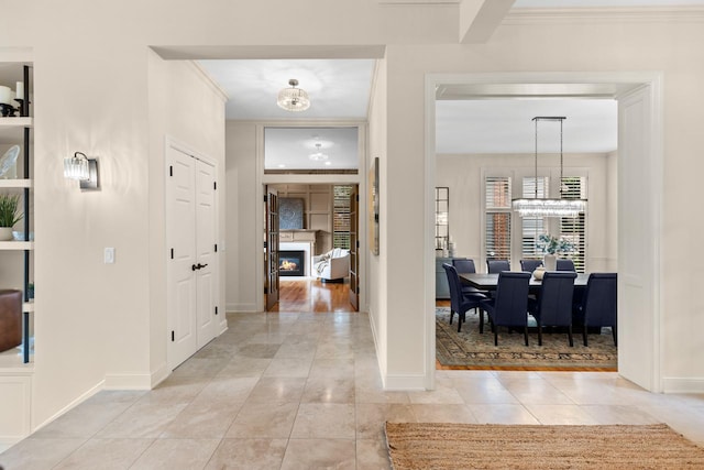 11193 Bluestem Ln, Eden Prairie, MN 55347 - entrance foyer featuring a chandelier, a glass covered fireplace, crown molding, and light tile patterned flooring