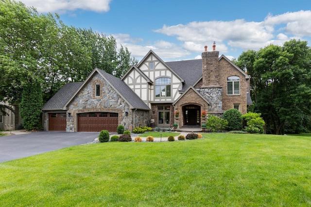11193 Bluestem Ln, Eden Prairie, MN 55347 - tudor home featuring stone siding, driveway, a front yard, a chimney, and an attached garage