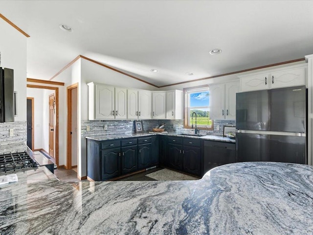 33498 175th St NE, Morrill Twp, MN 56329 - kitchen with freestanding refrigerator, ornamental molding, light stone countertops, white cabinetry, and tasteful backsplash