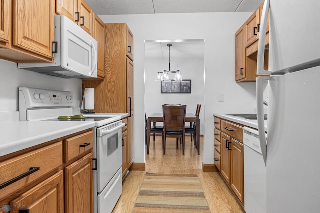 1110 3rd Ave N Unit 201E, Fargo, ND 58102 - kitchen with white appliances, light wood-style floors, light countertops, a chandelier, and brown cabinets