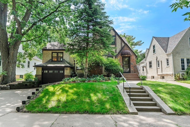 947 Stryker Ave W, Saint Paul, MN 55118 - tudor-style house featuring brick siding, a front yard, an attached garage, and driveway