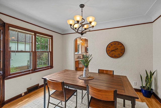 947 Stryker Ave W, Saint Paul, MN 55118 - dining room featuring arched walkways, light wood-style flooring, a chandelier, and a textured wall