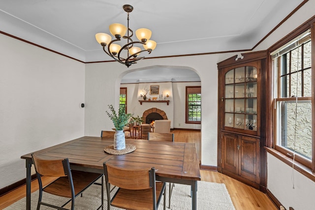 947 Stryker Ave W, Saint Paul, MN 55118 - dining space featuring arched walkways, a chandelier, light wood-type flooring, and a lit fireplace