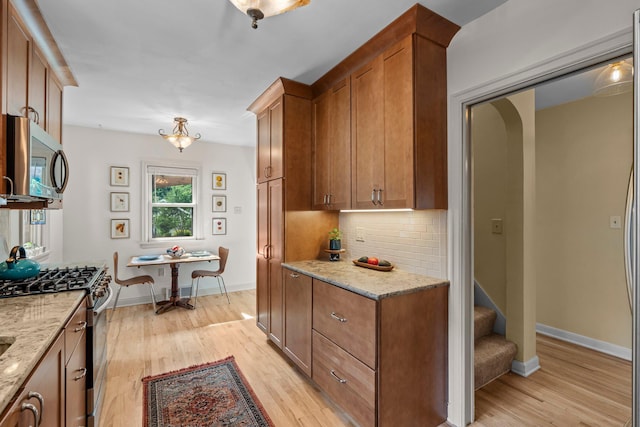 947 Stryker Ave W, Saint Paul, MN 55118 - kitchen featuring appliances with stainless steel finishes, light wood finished floors, brown cabinetry, backsplash, and light stone countertops