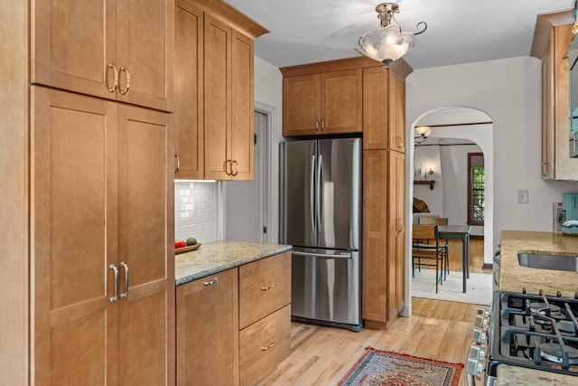 947 Stryker Ave W, Saint Paul, MN 55118 - kitchen with freestanding refrigerator, arched walkways, light wood-style floors, and light stone countertops