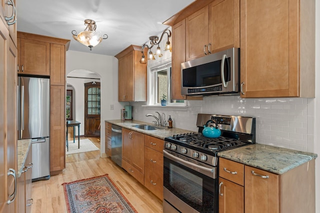 947 Stryker Ave W, Saint Paul, MN 55118 - kitchen with stainless steel appliances, arched walkways, light wood finished floors, tasteful backsplash, and light stone counters