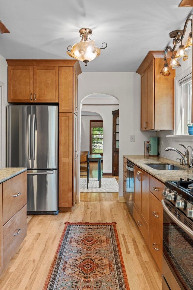 947 Stryker Ave W, Saint Paul, MN 55118 - kitchen with appliances with stainless steel finishes, arched walkways, light wood finished floors, light stone countertops, and brown cabinets