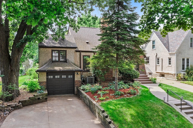 947 Stryker Ave W, Saint Paul, MN 55118 - english style home featuring brick siding, a garage, concrete driveway, a front lawn, and stairway