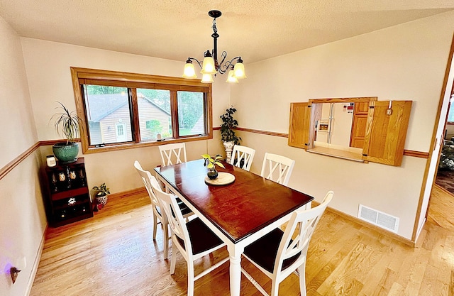 44512 276th Ln, Aitkin, MN 56431 - dining area featuring a chandelier, light wood finished floors, and a textured ceiling