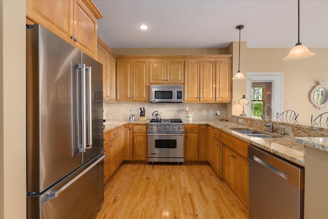 238 Muirfield Trl, Hudson, WI 54016 - kitchen with high quality appliances, light stone counters, light wood-style floors, decorative backsplash, and a peninsula