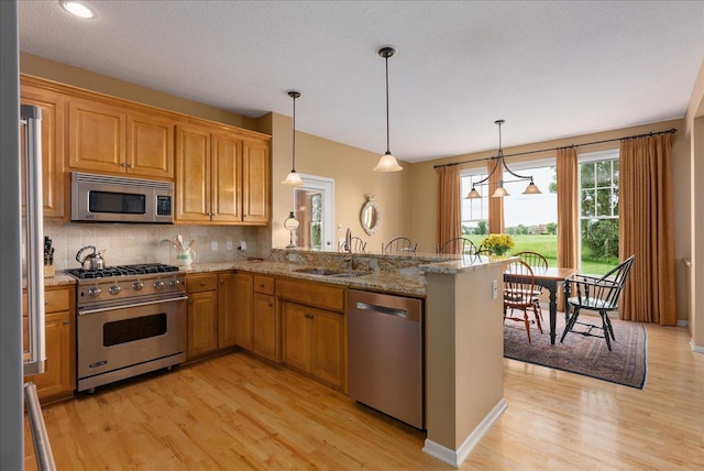 238 Muirfield Trl, Hudson, WI 54016 - kitchen with appliances with stainless steel finishes, light wood-style floors, tasteful backsplash, a peninsula, and light stone countertops