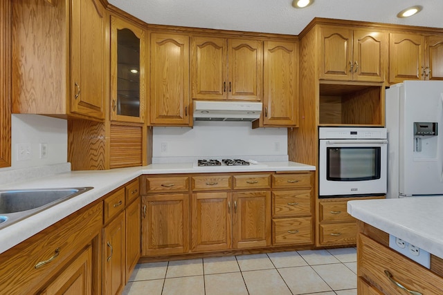 42767 190th Ave, Holding Twp, MN 56340 - kitchen featuring white appliances, under cabinet range hood, brown cabinets, glass insert cabinets, and light countertops