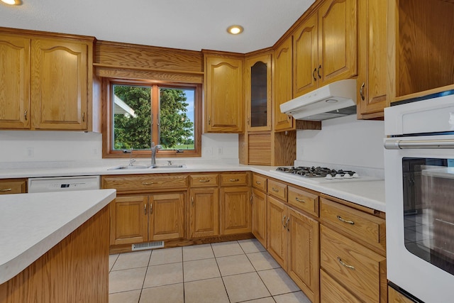 42767 190th Ave, Holding Twp, MN 56340 - kitchen with white appliances, under cabinet range hood, light countertops, brown cabinets, and light tile patterned floors