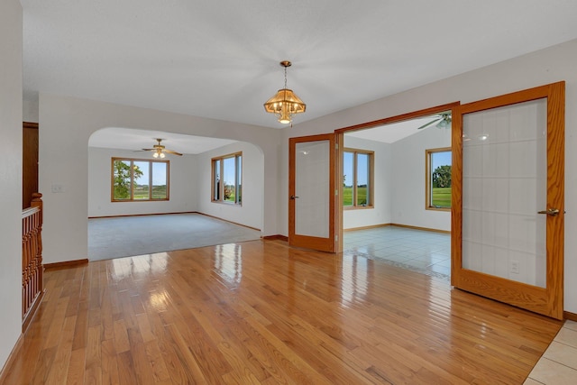 42767 190th Ave, Holding Twp, MN 56340 - unfurnished living room featuring arched walkways, light wood-style flooring, ceiling fan, and a chandelier
