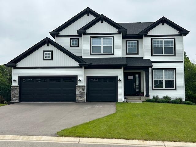 1977 Dahlia Dr, Shakopee, MN 55379 - view of front of house featuring a front yard, driveway, a garage, and board and batten siding