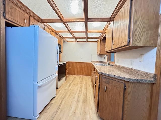 517 2nd St NW, Menahga, MN 56464 - kitchen with white appliances, light wood finished floors, wainscoting, coffered ceiling, and brown cabinetry