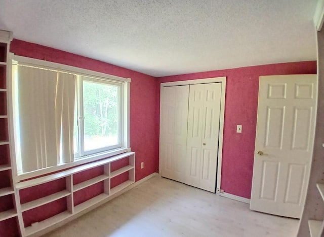 37059 Pinewood Dr, Lawrence Twp, MN 55709 - unfurnished bedroom with a textured ceiling, a closet, and wood finished floors