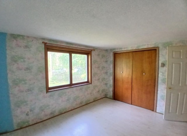 37059 Pinewood Dr, Lawrence Twp, MN 55709 - unfurnished bedroom with a closet, wallpapered walls, and wood finished floors