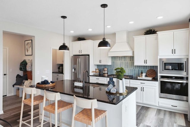 2963 Trinity Dr, Shakopee, MN 55379 - kitchen with appliances with stainless steel finishes, premium range hood, dark countertops, light wood finished floors, and recessed lighting