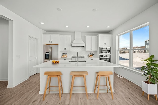 2963 Trinity Dr, Shakopee, MN 55379 - kitchen with stainless steel appliances, custom range hood, a breakfast bar area, a kitchen island with sink, and recessed lighting