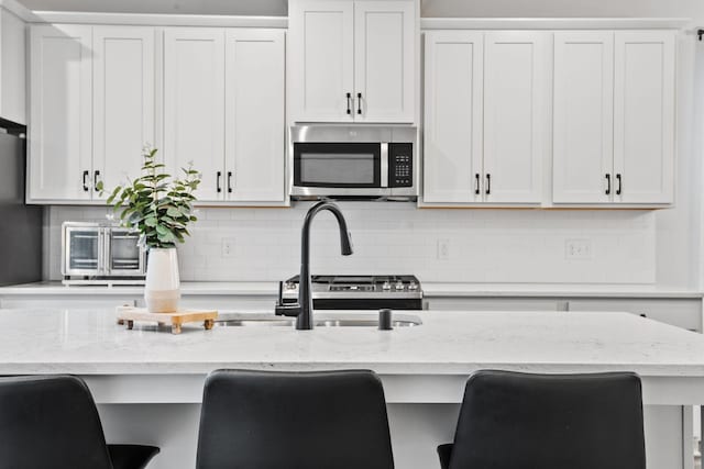 8612 Kenyon Ct NE Unit A, Blaine, MN 55449 - kitchen with stainless steel microwave, a kitchen bar, and backsplash