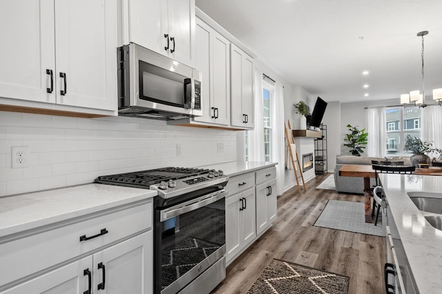 8612 Kenyon Ct NE Unit A, Blaine, MN 55449 - kitchen with stainless steel appliances, white cabinets, light wood-style floors, tasteful backsplash, and recessed lighting