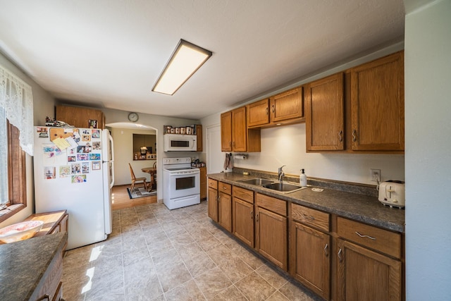 49227 US Highway 59, Dunn Twp, MN 56587 - kitchen with white appliances, arched walkways, dark countertops, and brown cabinetry