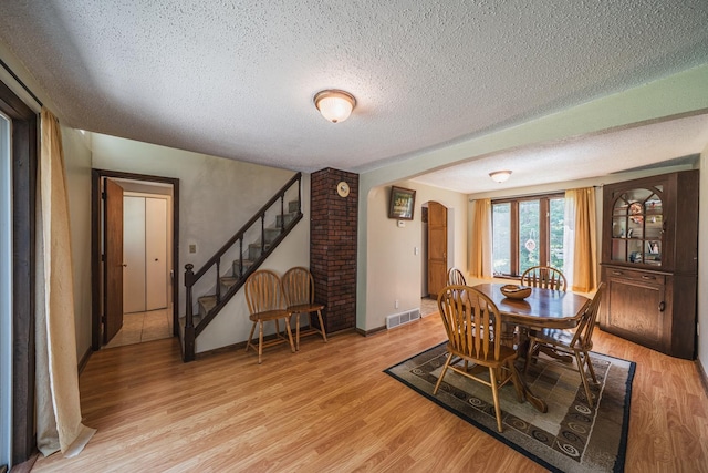 49227 US Highway 59, Dunn Twp, MN 56587 - dining space featuring arched walkways, light wood-type flooring, a textured ceiling, and stairs