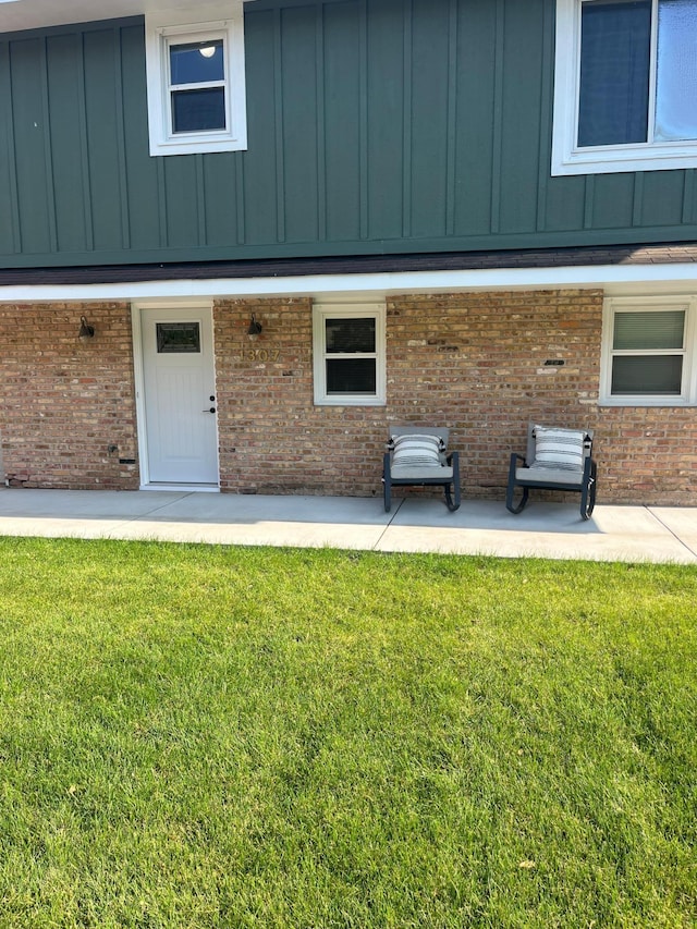 1307 20th St W, Hastings, MN 55033 - view of exterior entry with board and batten siding, a yard, brick siding, and a patio