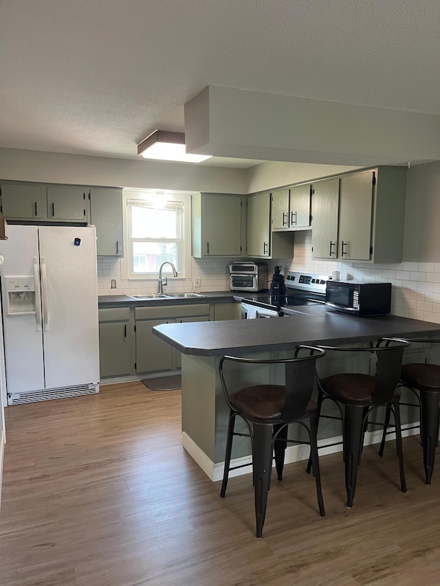 1307 20th St W, Hastings, MN 55033 - kitchen featuring white refrigerator with ice dispenser, black microwave, electric range, a peninsula, and decorative backsplash
