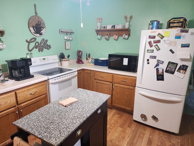 105 Main St, Brownsdale, MN 55918 - kitchen featuring white appliances, light countertops, light wood finished floors, brown cabinetry, and a center island
