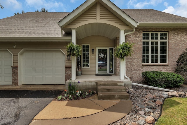504 3rd St N, Sartell, MN 56377 - view of exterior entry featuring an attached garage, a shingled roof, driveway, and brick siding