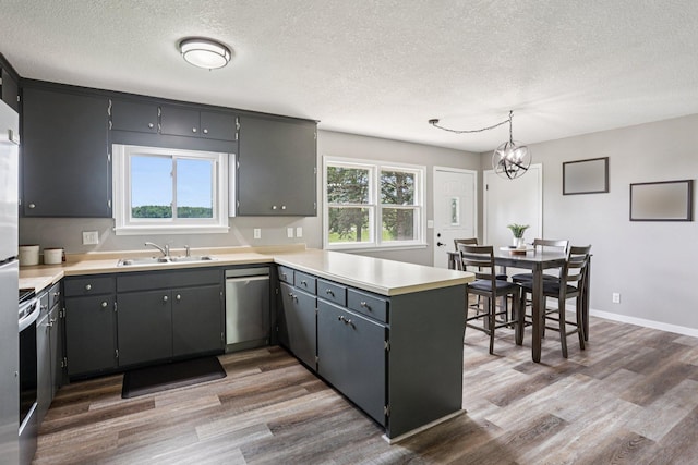 559 State Highway 35, East Farmington, WI 54020 - kitchen with appliances with stainless steel finishes, wood finished floors, a textured ceiling, a peninsula, and a chandelier