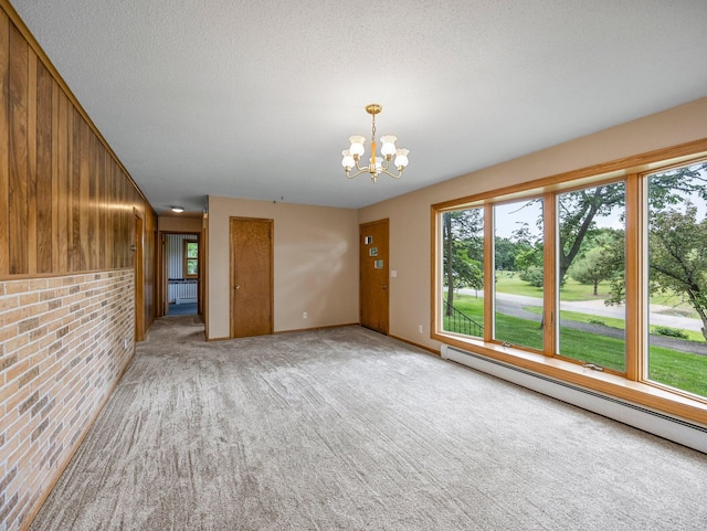 8545 70th St NW, Annandale, MN 55302 - unfurnished living room featuring a baseboard heating unit, a chandelier, light carpet, brick wall, and a textured ceiling