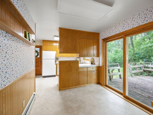 8545 70th St NW, Annandale, MN 55302 - kitchen with freestanding refrigerator, wallpapered walls, a baseboard heating unit, wainscoting, and brown cabinetry
