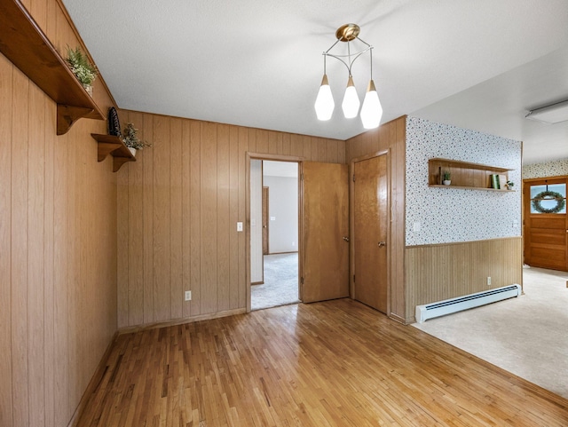 8545 70th St NW, Annandale, MN 55302 - empty room with a baseboard radiator, light wood finished floors, wooden walls, wallpapered walls, and a chandelier