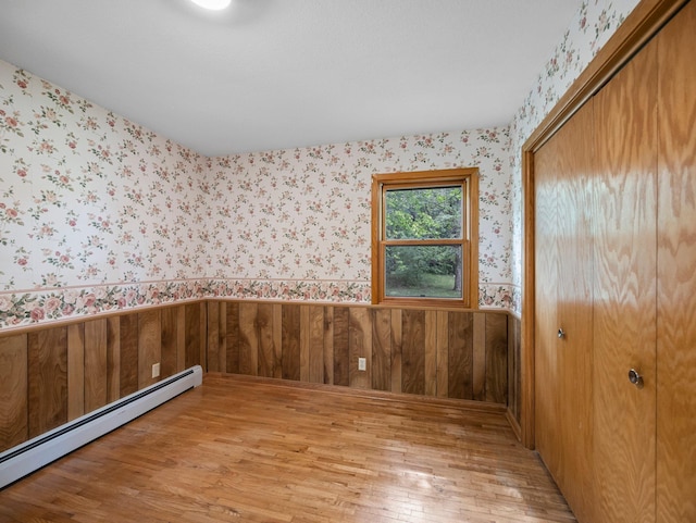 8545 70th St NW, Annandale, MN 55302 - unfurnished room with a baseboard radiator, light wood-type flooring, wainscoting, wallpapered walls, and wood walls