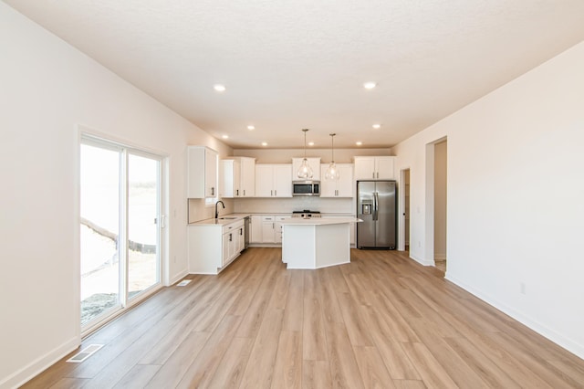 18665 Kennedy St NW, Elk River, MN 55330 - kitchen featuring stainless steel appliances, light wood-style flooring, a kitchen island, light countertops, and white cabinetry