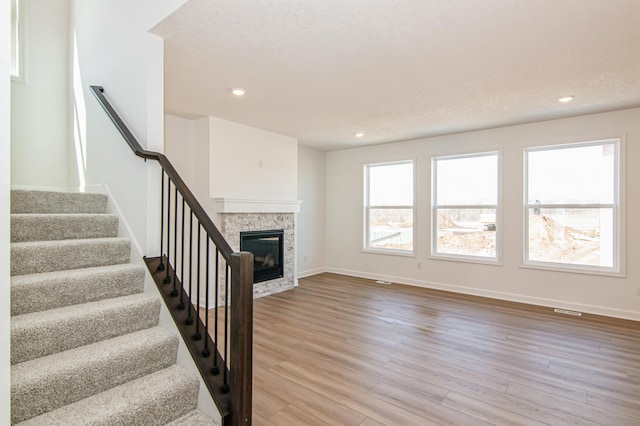 18665 Kennedy St NW, Elk River, MN 55330 - unfurnished living room featuring light wood finished floors, recessed lighting, a glass covered fireplace, and stairway